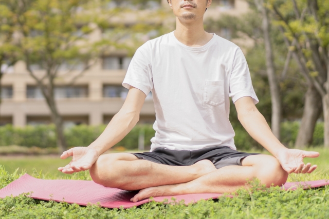 芝生の上で瞑想を行う男性の画像