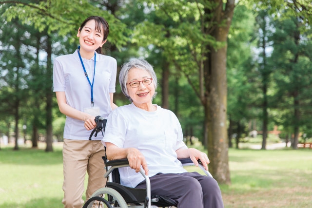 介護士の女性と、車椅子に乗っている高齢女性の画像