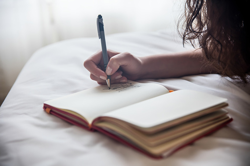 ノートにペンで何か書いている人の手元